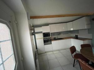 a kitchen with white cabinets and a table with chairs at Gite La Maison Blanche in Drouvin-les-Marais +3 photos