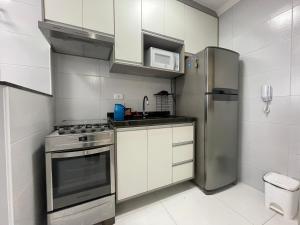 a kitchen with a stainless steel refrigerator and white cabinets at Apartamento com Varanda Gourmet e Wi-Fi Rápido - Renove as Energinas Vila Caiçara Praia Grande in Praia Grande