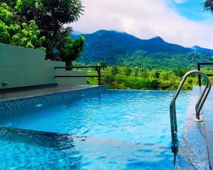 a swimming pool with mountains in the background at Hillway Boutique Resort in Vythiri