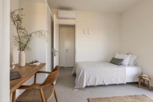a bedroom with a bed and a desk and a table and chair at GN7 Villas in Kithnos