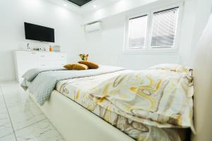 a white bedroom with a bed and a television at Archi's Apartament in Galaţi