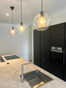 a kitchen with a sink and three pendant lights at la maison Sapanomar in Beaumes-de-Venise