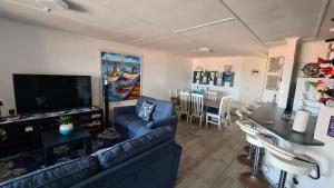 a living room with a blue couch and a tv at Corona Del Mar 23 in Uvongo Beach