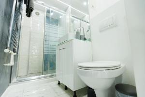 a white bathroom with a toilet and a shower at Archi's Apartament in Galaţi +6 photos