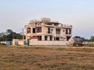迪布鲁加尔Dibru Ghar Homestay的田野前有坦克的建筑物