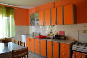 uma cozinha com armários laranja e uma mesa em Guest house Ema em Daruvar