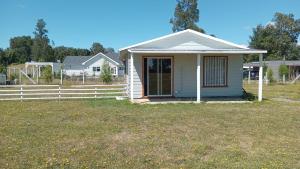 a small white house with a fence in a yard at Cabaña San Isidro in Coipue