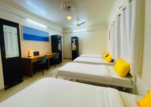 a room with four beds and a desk with a laptop at Bern Hostel By Vibe Village in Pune