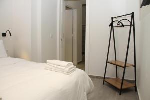 a bedroom with a white bed and a wooden chair at Pirgos Cozy Apartment for 4 by MPS in Pyrgos