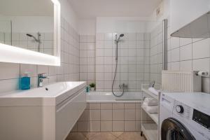 a white bathroom with a tub and a washing machine at Stadtapartments Luna by Cosy Homes in Villach