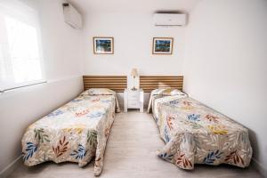 deux lits dans une chambre aux murs blancs dans l'établissement Encantador apartamento en Barajas by beBalmy, à Madrid