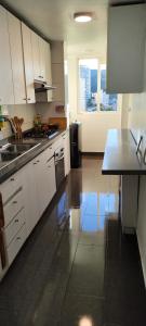 a kitchen with white cabinets and a sink and a table at Ocean View & Pool Family Apartment 1P in Valparaíso