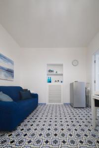a living room with a blue couch and a refrigerator at Le Due Sorelle in Vietri sul Mare