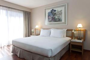 a bedroom with a large white bed and a window at NH Córdoba Urbano in Córdoba