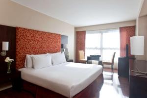 a bedroom with a large white bed and a desk at NH Córdoba Urbano in Córdoba