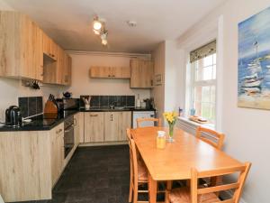 a kitchen with a wooden table and wooden cabinets at The Well House Apartment in Watchet