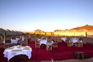 a group of tables and chairs in a field with tents at Touaregs Camp Erg Lihoudi in Mhamid +37 photos