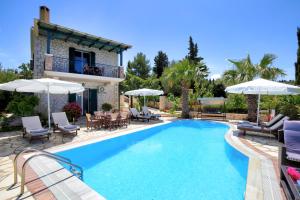 a swimming pool with chairs and umbrellas next to a house at Villas Goudis in Tsoukaladhes