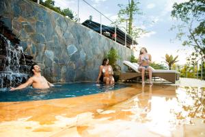 a group of people sitting in a swimming pool with a waterfall at GreenOriental Resort in La Vega
