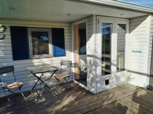 a porch with chairs and a table on a house at Mobilhome with terrace in Saint-Pardoux-Corbier