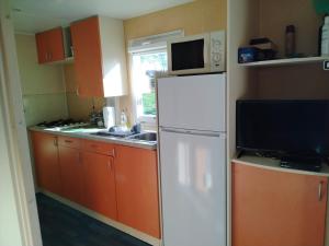 a kitchen with orange cabinets and a white refrigerator at Mobilhome with terrace in Saint-Pardoux-Corbier +8 photos