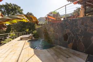 a swimming pool with a stone wall and a wooden deck at GreenOriental Resort in La Vega +67 photos