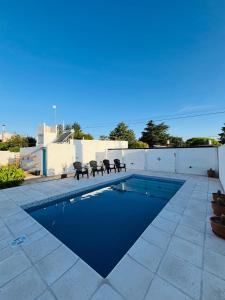 a swimming pool with chairs next to a house at Villanto apart Solo Adultos in Mina Clavero