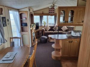 ML53 6 BERTH CARAVAN GOLDEN PALM CHAPET ST LEONARDs في شابيل سانت ليوناردز: مطبخ وغرفة معيشة مع طاولة وأريكة