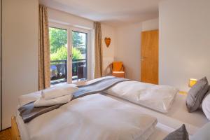 a bedroom with a large white bed with a window at Suite Werdenfels in Garmisch-Partenkirchen +3 photos