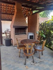 a wooden table and chairs with a brick oven at Chalés Monções in Ubatuba