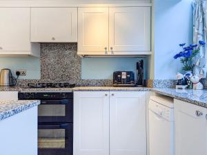 une cuisine avec des armoires blanches et des appareils noirs dans l'établissement Clifton Cottage - by Brighton Holiday Lets, à Brighton et Hove