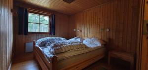a bed in a wooden room with a window at Sauna | Wi-Fi | Terrace | Wood stove | Cable TV in Lofsdalen