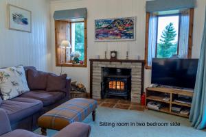 a living room with a tv and a fireplace at Ferroch the place with an amazing view! in Torridon