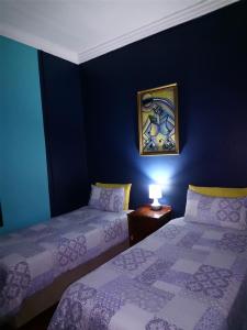a blue room with two beds and a picture on the wall at Hostel Villa Nova in Mossel Bay