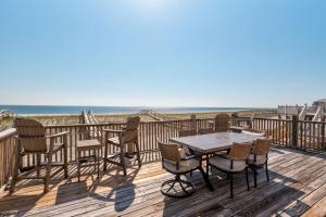 a deck with a table and chairs and the beach at Pour House in Dauphin Island