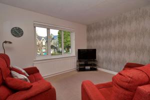 a living room with two red chairs and a television at Acer View in Bowness-on-Windermere