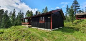 a black house on top of a grassy hill at Sauna | Wi-Fi | Terrace | Wood stove | Cable TV in Lofsdalen