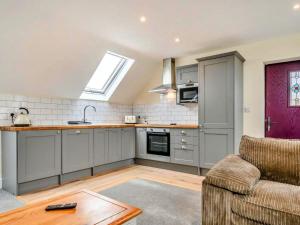 a kitchen with grey cabinets and a couch and a table at Little Rissington - The Studio Apartment in Little Rissington