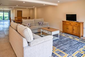 a living room with a couch and a tv at Little Rissington - Barn Seven in Little Rissington