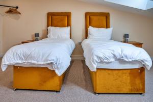 two beds in a room with white sheets and pillows at Little Rissington - Barn Seven in Little Rissington