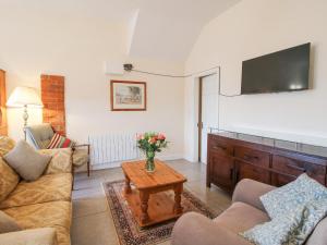 a living room with a couch and a table with a tv at Millstone Cottages - Granary Cottage in Shrewsbury