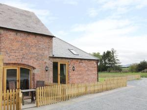 a brick building with a wooden fence around it at Millstone Cottages - Granary Cottage in Shrewsbury
