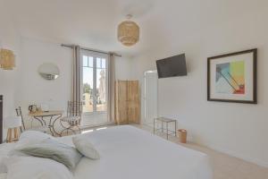 a white bedroom with a large bed and a table at La Garoupe-Gardiole in Antibes