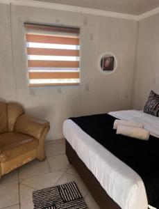 a bedroom with a bed and a couch and a window at Begin Guesthouse in Ermelo +3 photos