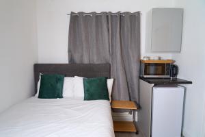 a bed with green and white pillows and a microwave at Snooze Luxe House in Dallington