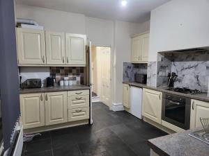 a kitchen with white cabinets and marble counter tops at Cozy Haven Near Leicester University and General Hospital in Leicester +12 photos