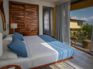 a bedroom with a bed and a large window at Suites La Hacienda in Puerto Escondido