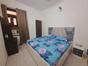 a bedroom with a bed with a blue comforter at Green Bacchus stays Self Check-In in Gurgaon