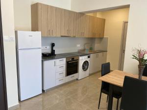 a kitchen with a white refrigerator and a table at Seaside Luxury Flat in Harbour Tourist Area in Paphos City