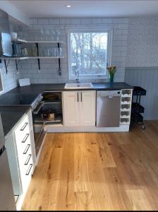 eine Küche mit weißen Schränken und einem Holzboden in der Unterkunft Sea Breeze Cottage in Färjestaden